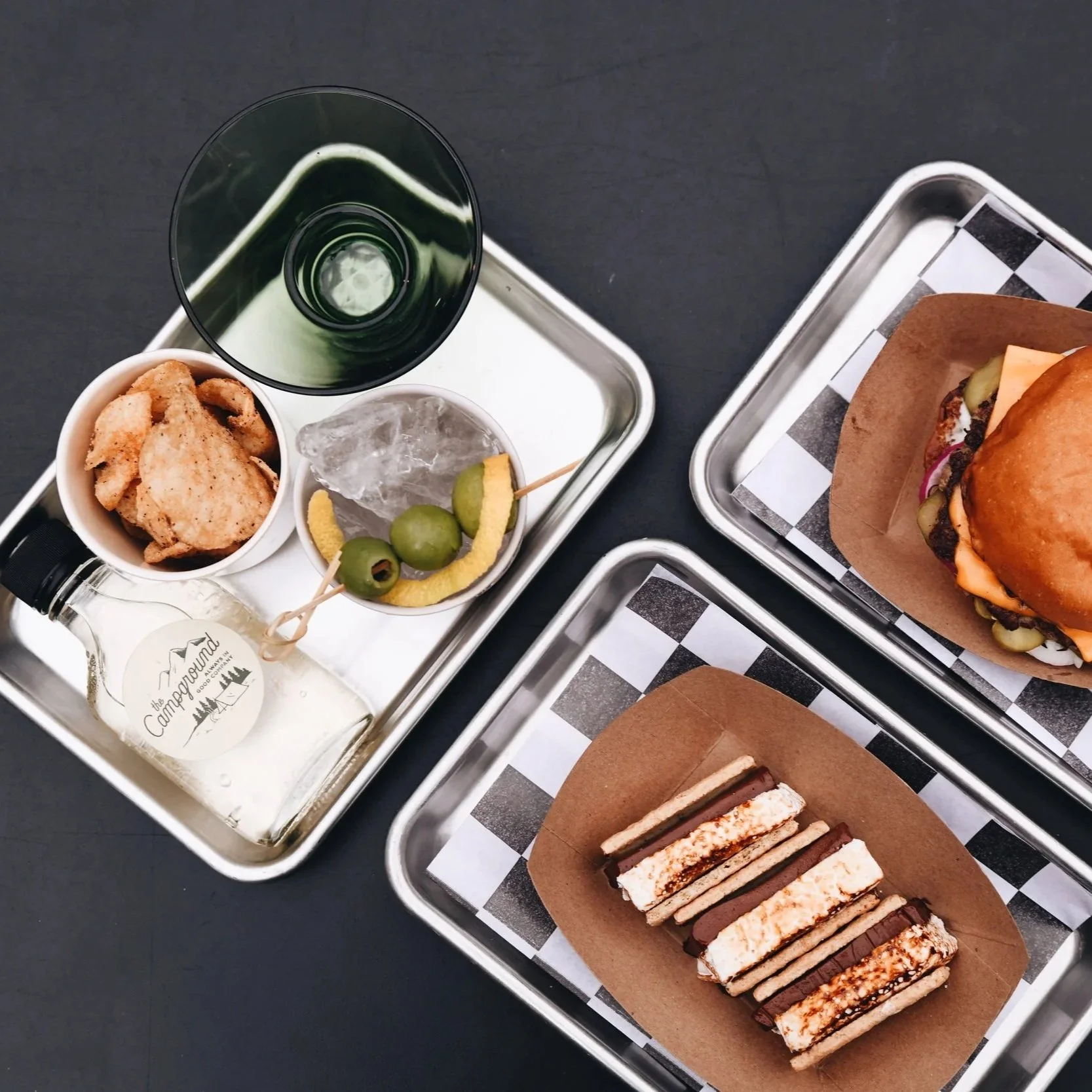 Close up image of a hamburger, s'mores, and a martini tray