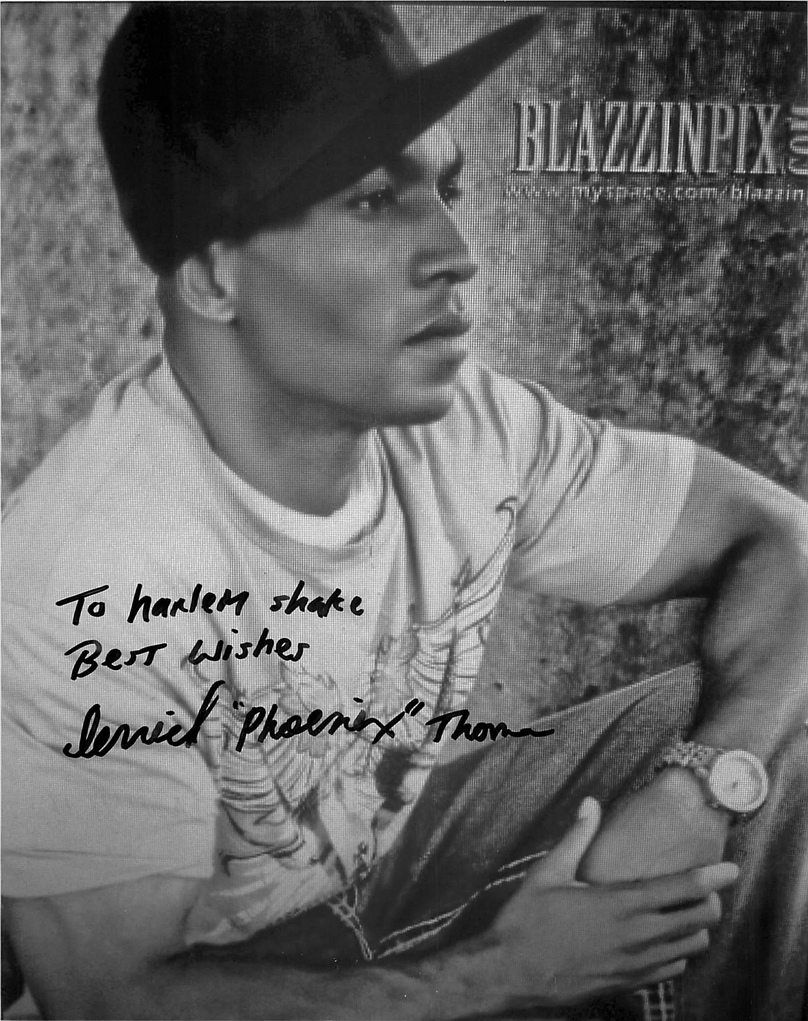 Black and white photograph of a young man with wavy hair, wearing a hoodie with a graphic design, sitting outdoors with trees in the background. Handwritten message on the image reads, "To harle shake, Best Wisher, David 'Phoenix' Thorne."