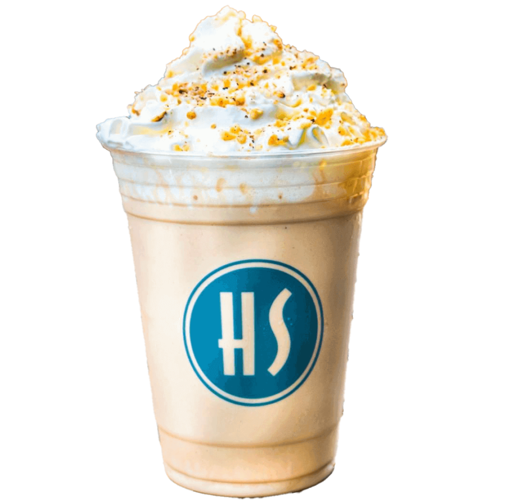 A large caramel-flavored frappuccino topped with whipped cream and caramel bits, served in a clear plastic cup with a blue and white logo.