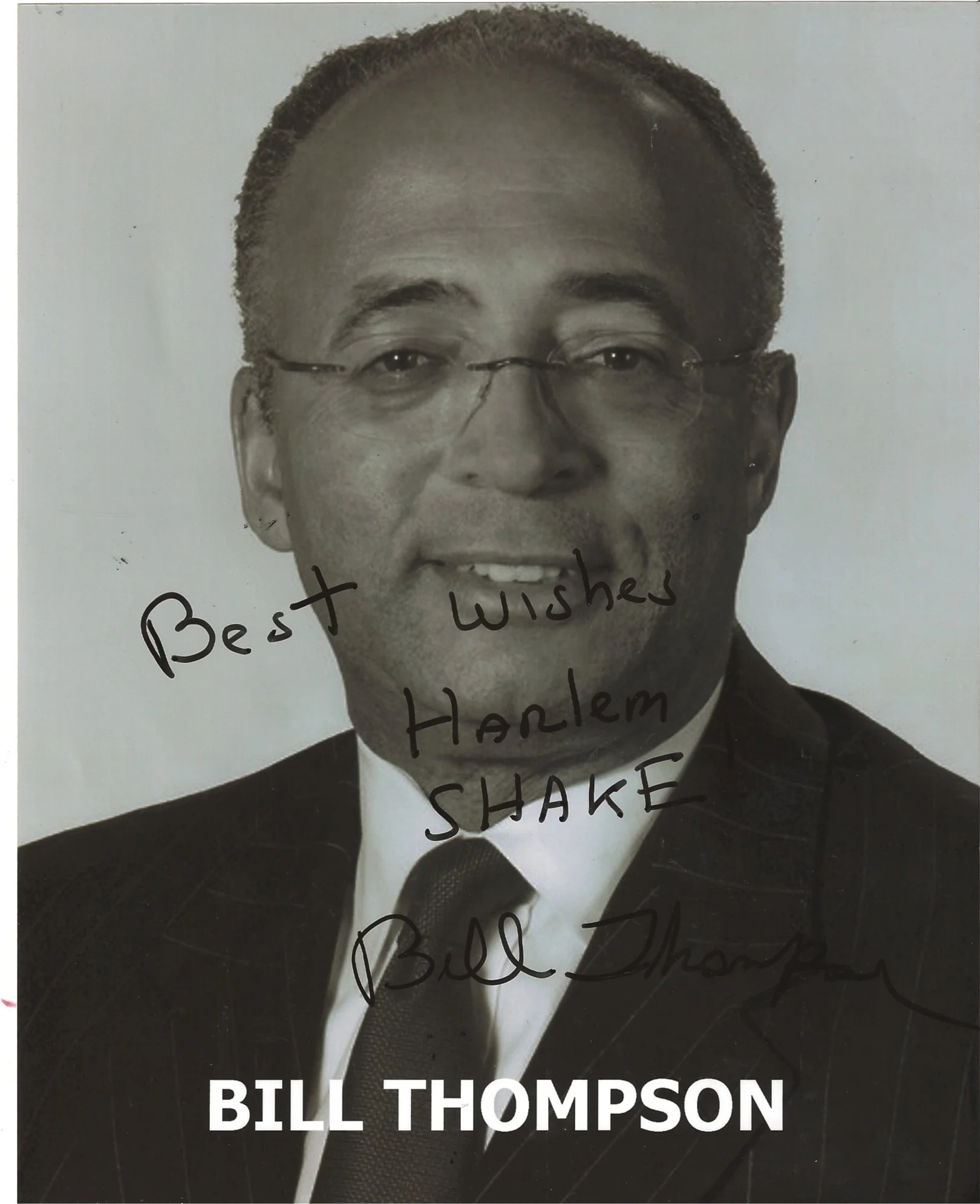 Black and white portrait of Bill Thompson wearing a suit and tie, with handwritten message overlaying the photo that says 'Best Wishes Hank.'