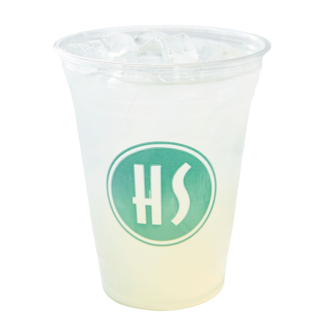 A clear plastic cup with ice and a white beverage, featuring a green logo with the letters 'HS' on the front.