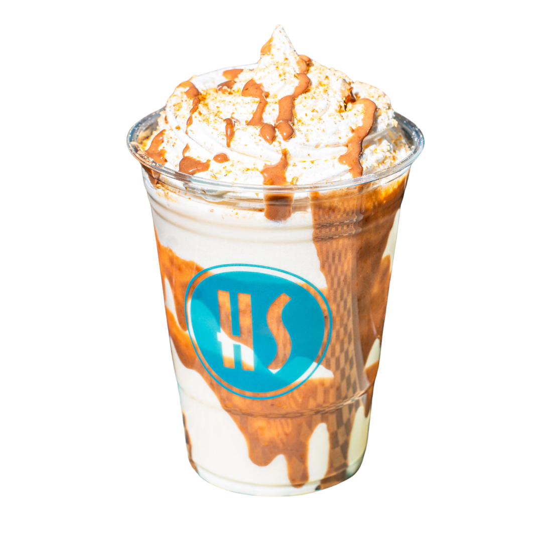 A caramel frappuccino with whipped cream and caramel drizzle in a plastic cup with a blue logo.