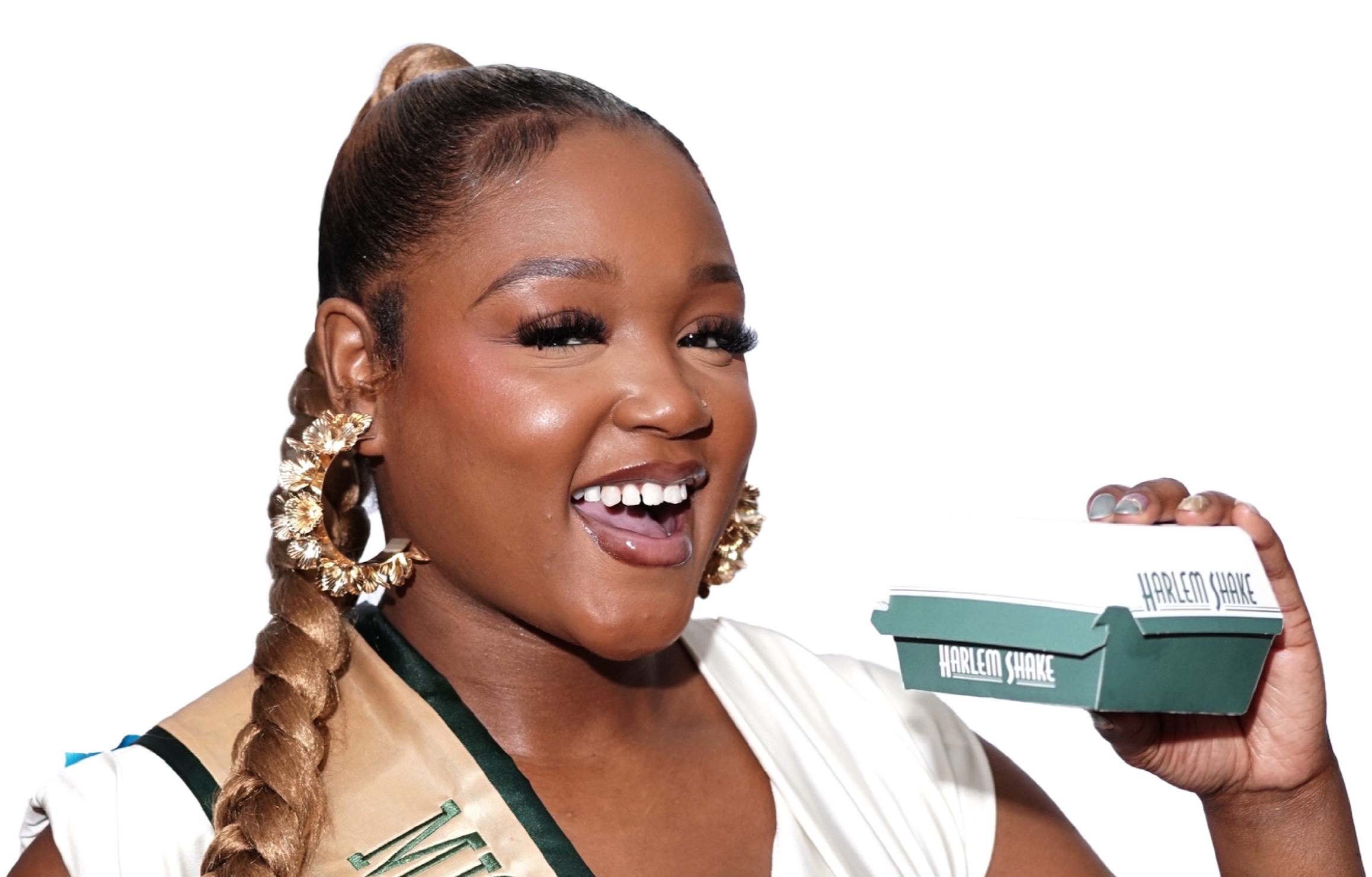 A woman with braided hair, gold earrings, and a white shirt holding a takeout box labeled Harlem Shake, smiling and looking joyful.