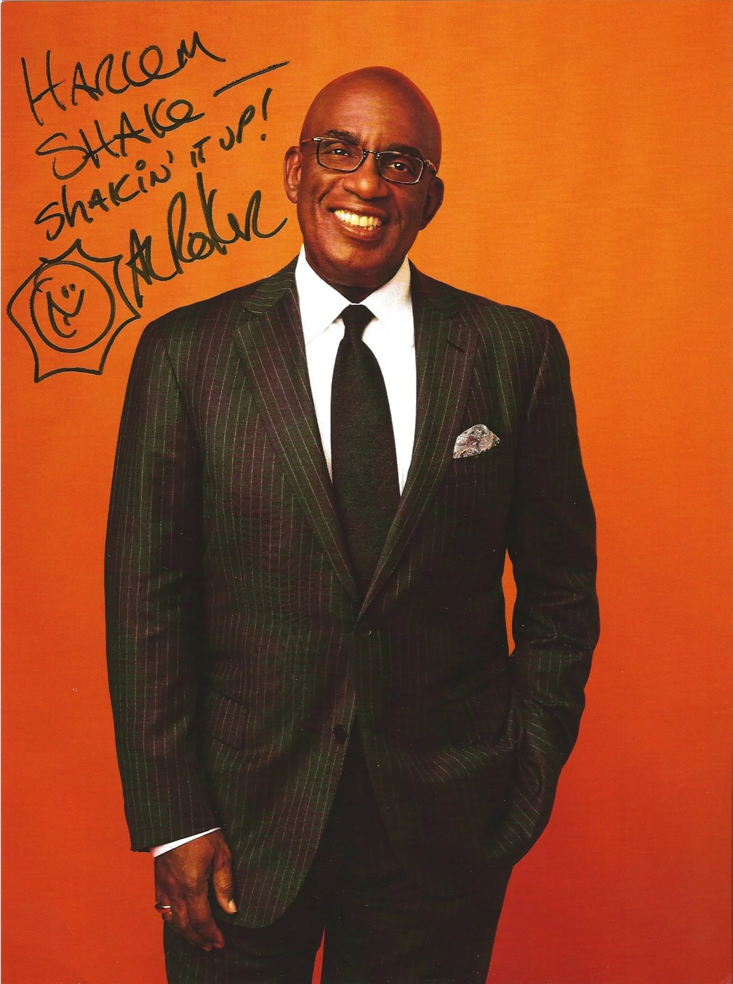 A smiling bald man with glasses wearing a dark plaid suit, white shirt, black tie, and pocket square standing in front of an orange background. Handwritten notes on the top left corner say 'HARLEM SHAKE!' and 'shaking it up!' with a small smiley face