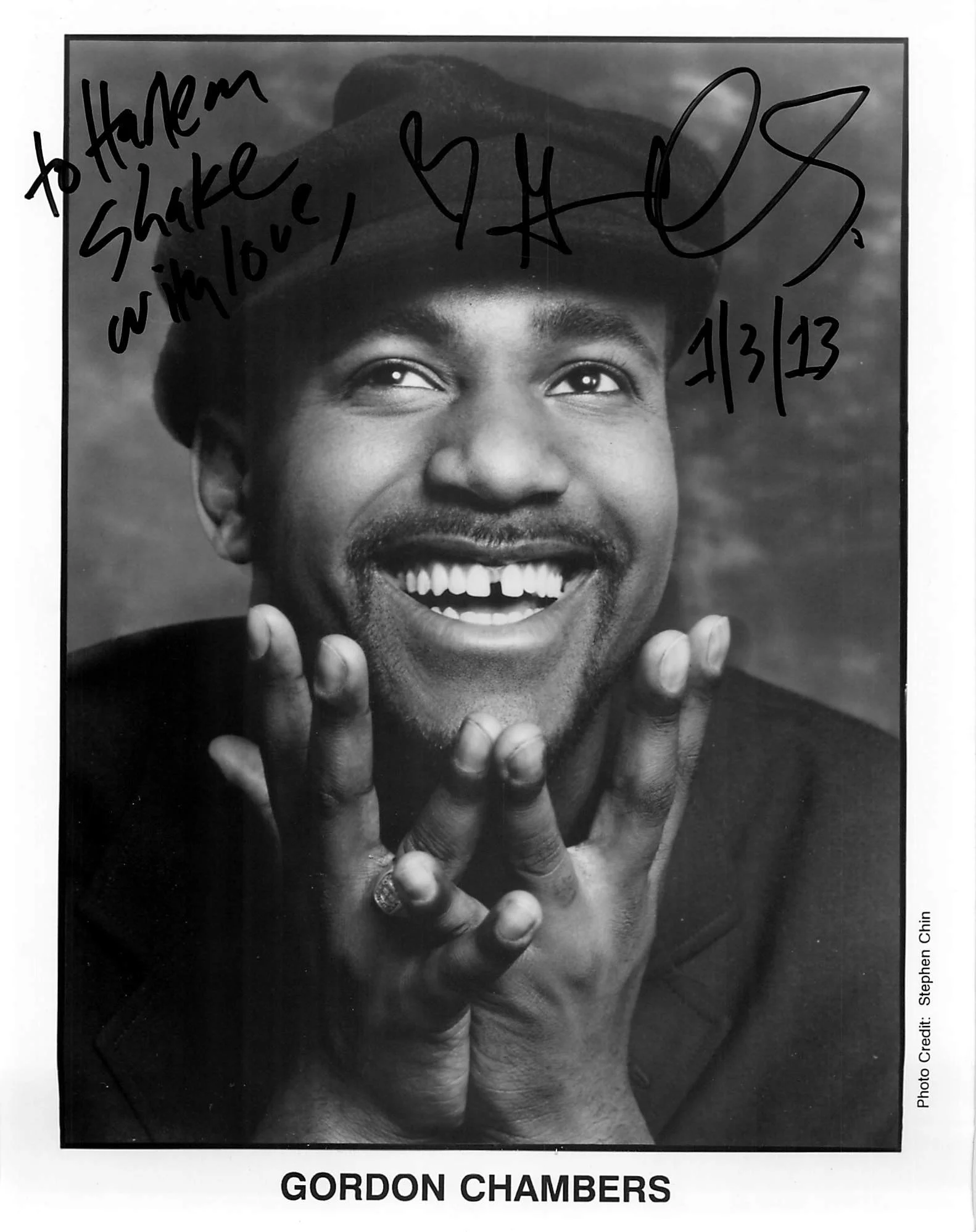Black and white promotional photo of Gordon Chambers with a close-up of his smiling face. He's wearing a hat, and handwritten text on the photo reads, "To Harem, Shake your love, 4/3/23." The image credits go to Stephen Chen. The bottom of the page d