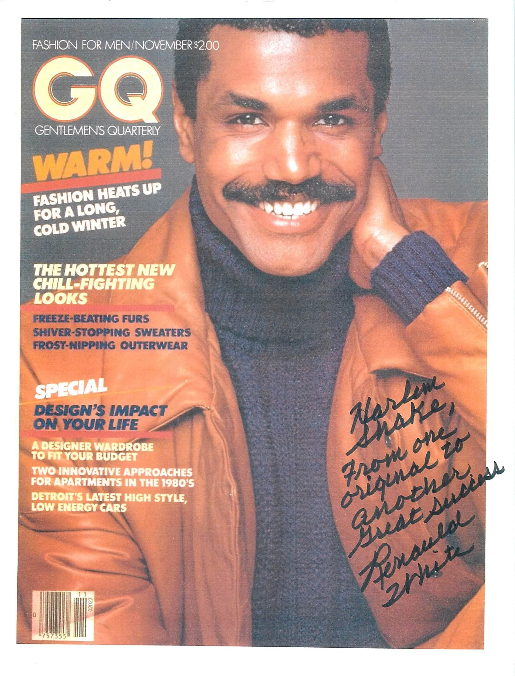 Cover of GQ magazine featuring a man with a mustache and dark hair, smiling. The magazine highlights fashion trends for winter, including freeze-beating furs and frost-nipping outerwear, and discusses design impacts on life. The man has a signature h