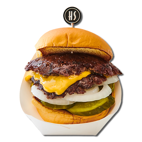 Juicy cheeseburger with melted cheese, onions, pickles, and a beef patty in a bun.