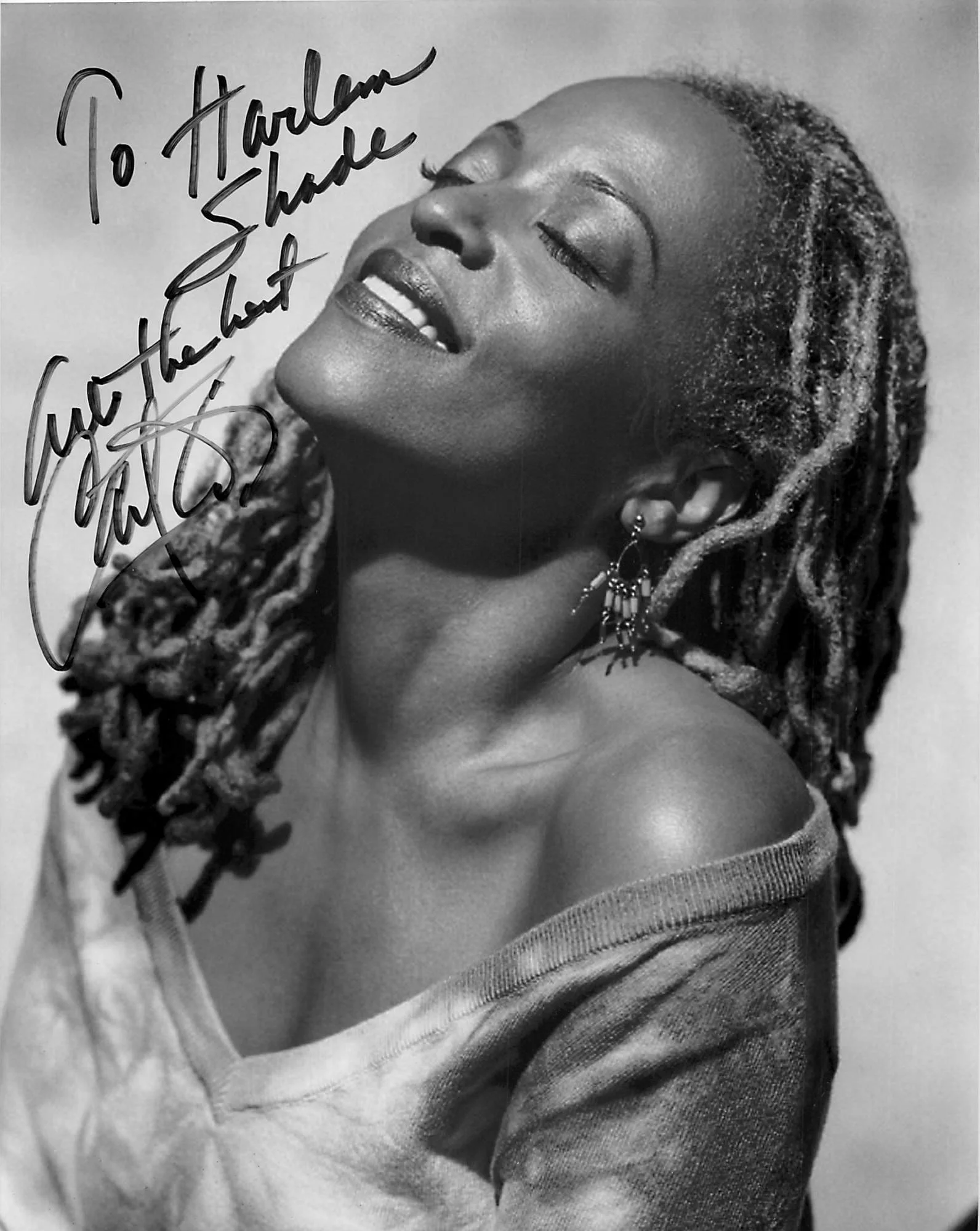 A joyful woman with dreadlocks smiling brightly, wearing earrings and a striped shirt.