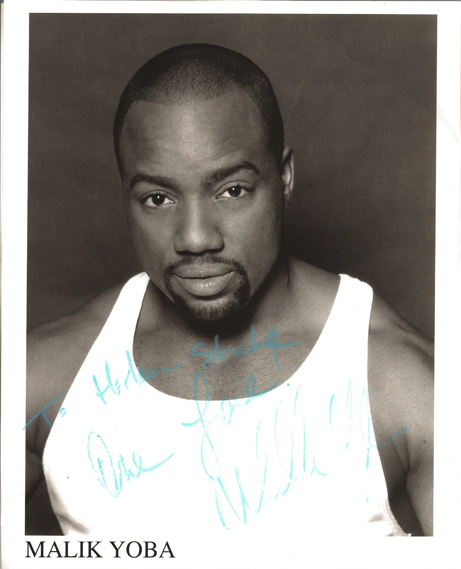 Close-up of a young African American man with short hair and facial hair, wearing a sleeveless white top, smiling slightly against a dark background, with handwritten blue text overlaid on the lower part of the image stating "Thank you" and "Malik Yo