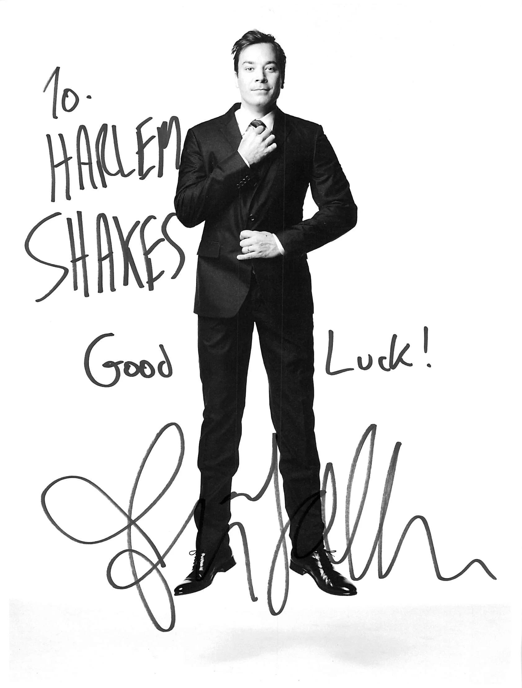 Black-and-white photo of a man in a suit standing with one hand on his chest. There is handwritten text on the image saying "To. Happy Shakes" and some additional words below that are partially visible.