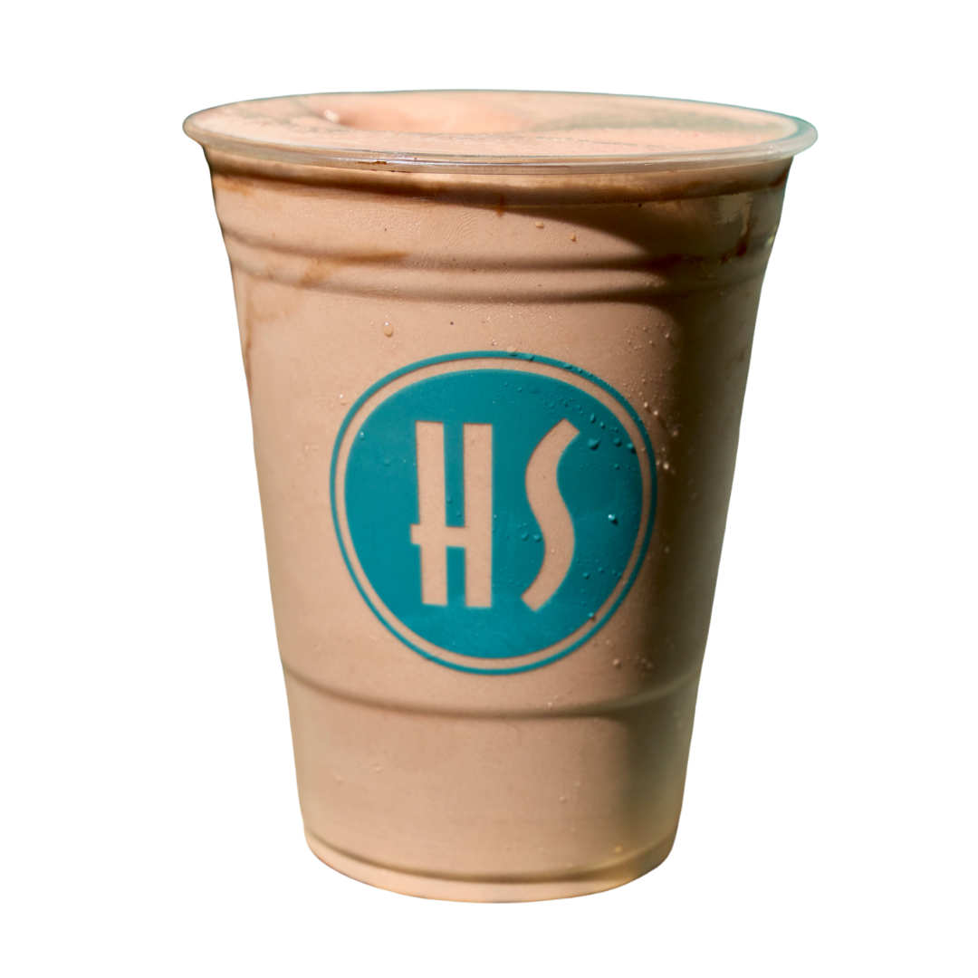 A disposable cup with a blue logo and the letters 'HS' on it, containing a light brown beverage, possibly a milkshake or smoothie.