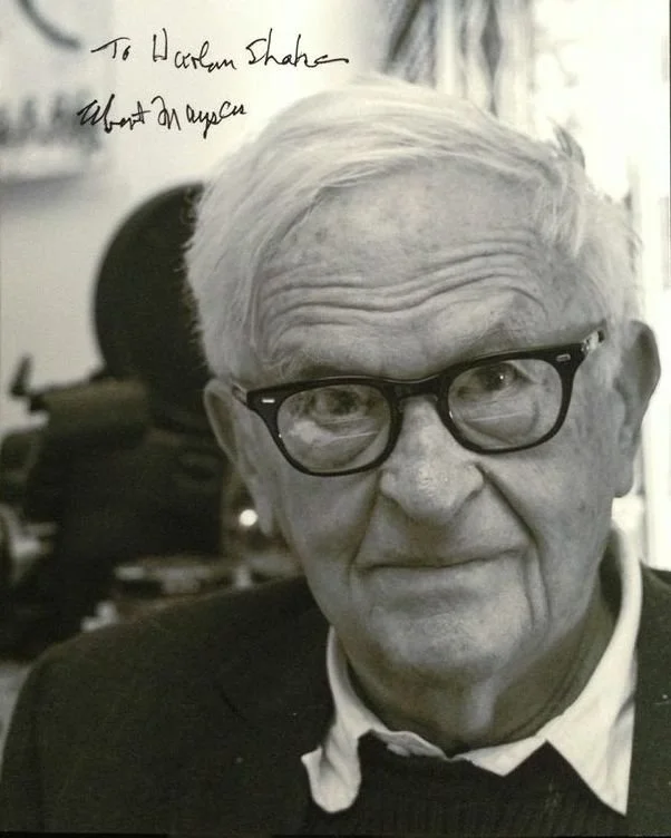 Close-up black and white photo of an elderly man with white hair, wearing glasses and a collared shirt. Handwritten note in the top left corner says, 'To Harley Shable, Wont An Angel.'