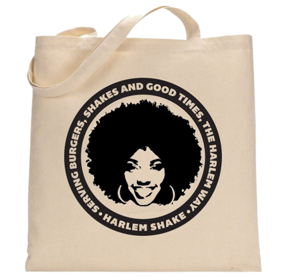 A beige reusable tote bag with a black circular logo featuring an illustration of a woman with curly hair, and text that reads "Shrimp Burgers, Shakes and Good Times! The Harlem Way. Harlem Shake".