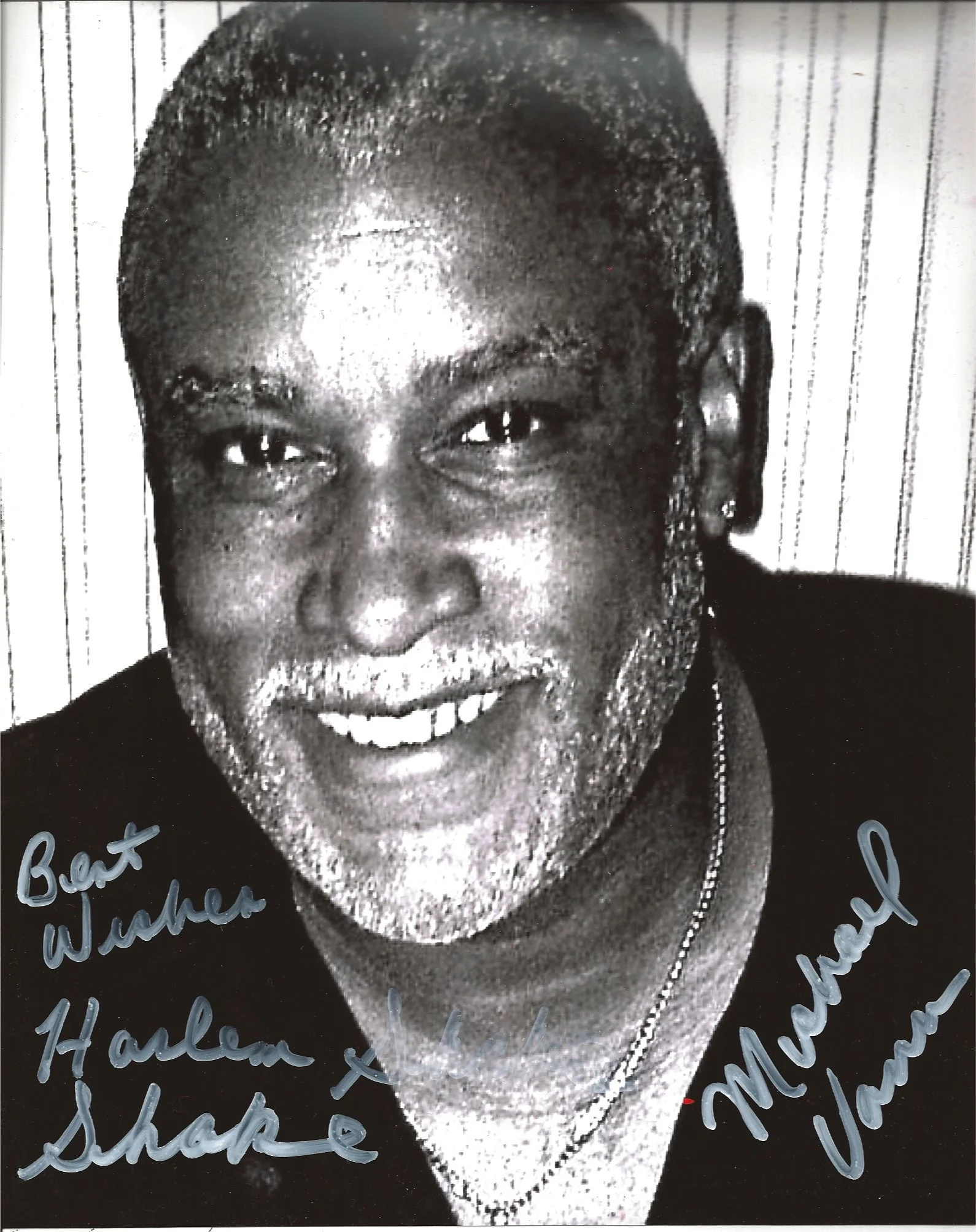 Black and white photograph of a person's face, smiling, with handwritten signatures and messages in blue ink overlayed on the bottom half of the image.