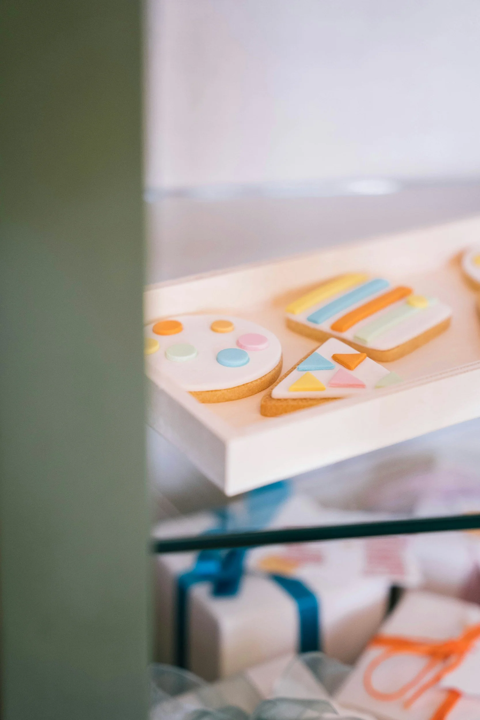 Colorful decorated cookies with pastel rainbow stripes, triangles, and dots on a white tray.