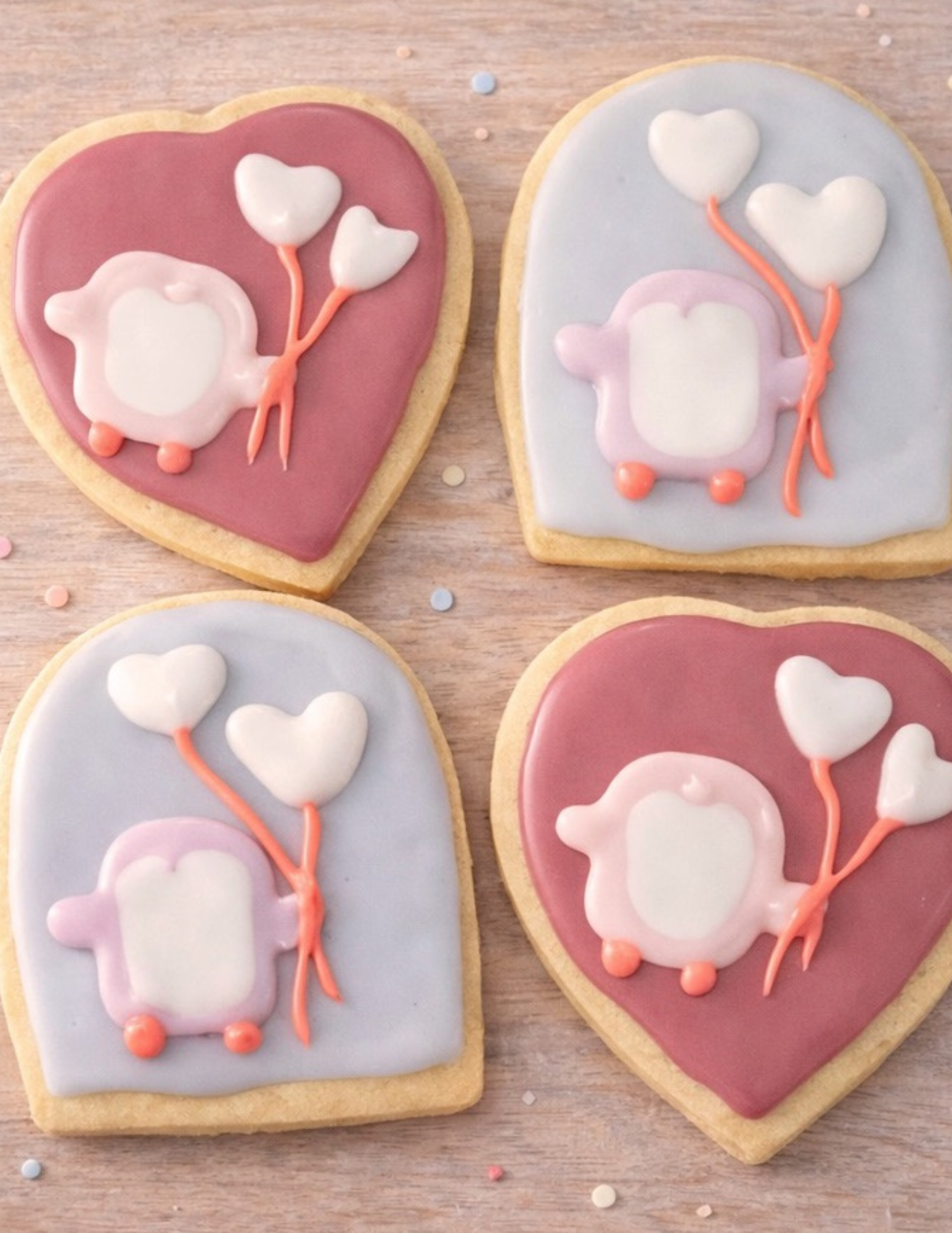Decorated cookies with pig and balloon designs on a wooden surface.