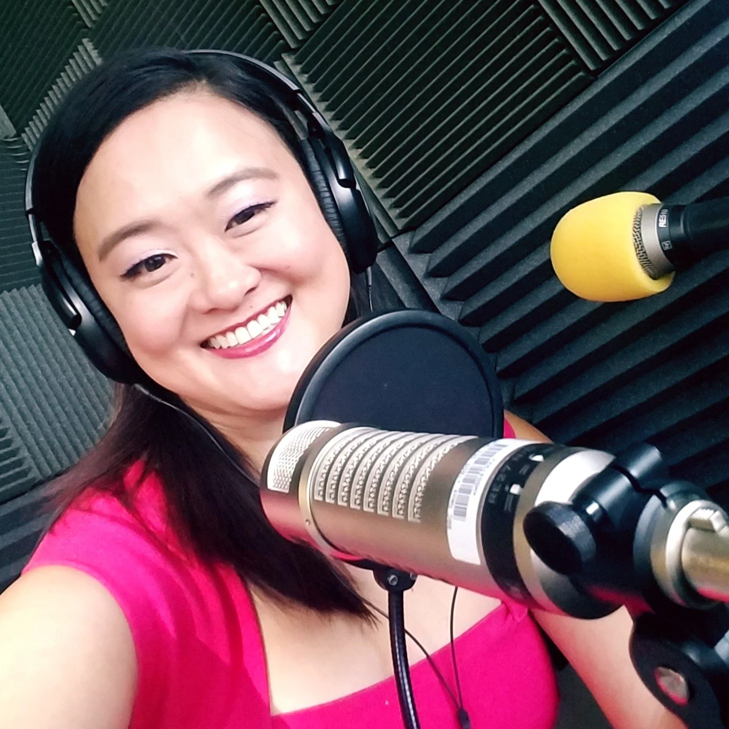 Mary Bowers in the BBC News recording studio, wearing headphones and smiling, with a microphone in front of her and soundproofing foam on the walls.