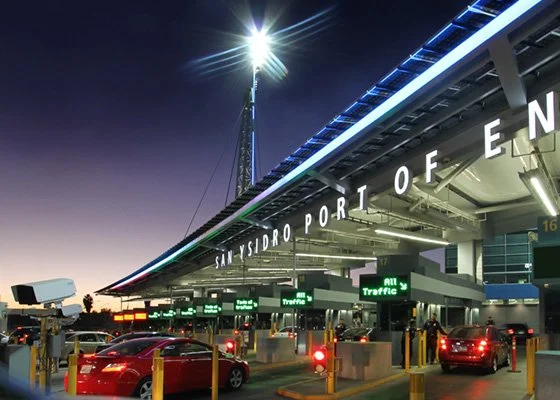 San Ysidro Port of Entry at sunset with cars and traffic signs.