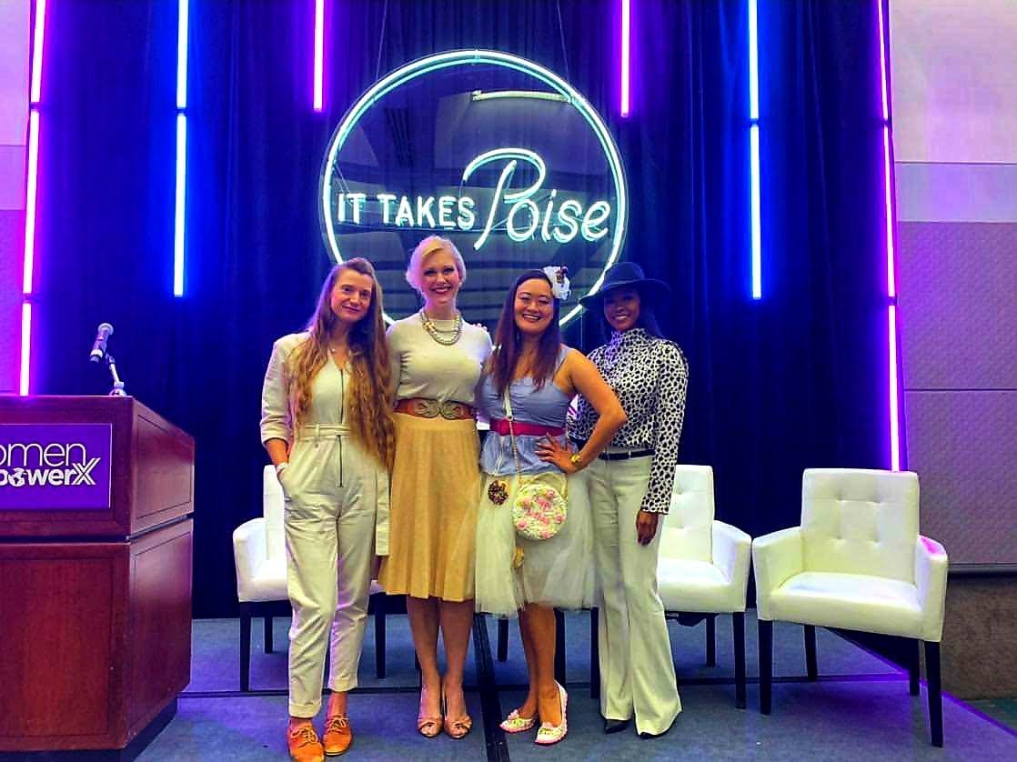 Panelists speakers at the Women Empower X Conference stand in front of a neon sign on the stage that says 'It Takes Poise.'