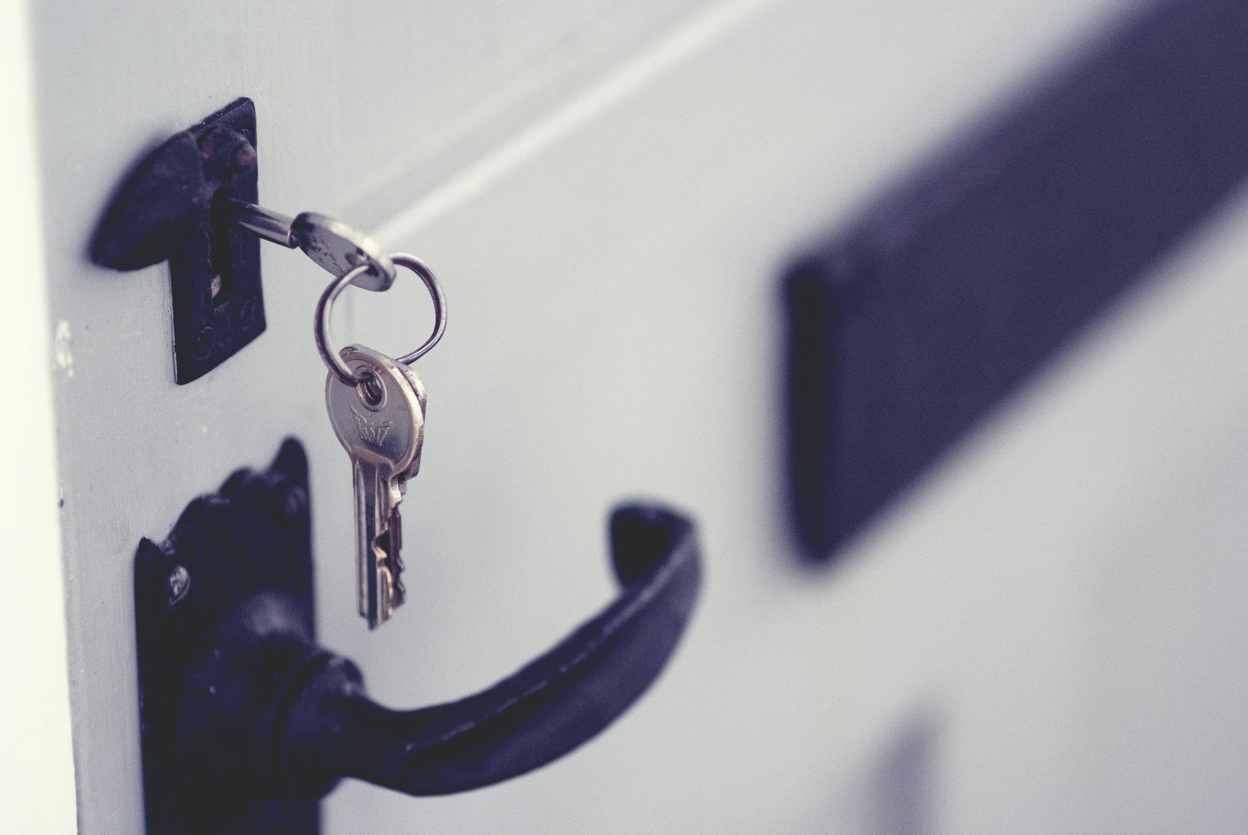Close-up of a key inserted into a lock on a white locker door.