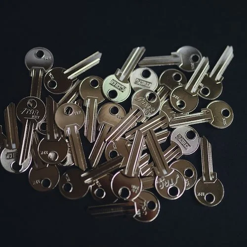 A pile of silver and black keys scattered on a dark surface.