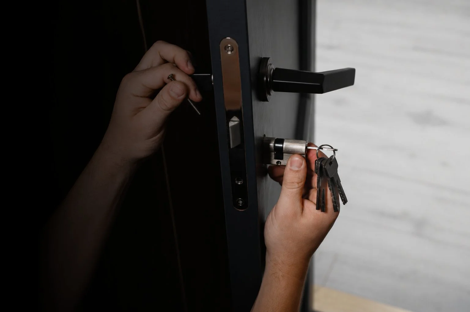 Person inserting a key into a door lock with multiple keys attached to a keyring.