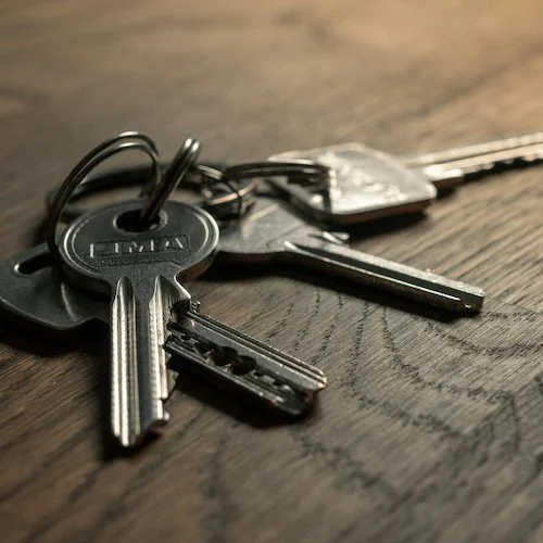 A close-up of a set of keys on a wooden surface, including house and car keys.