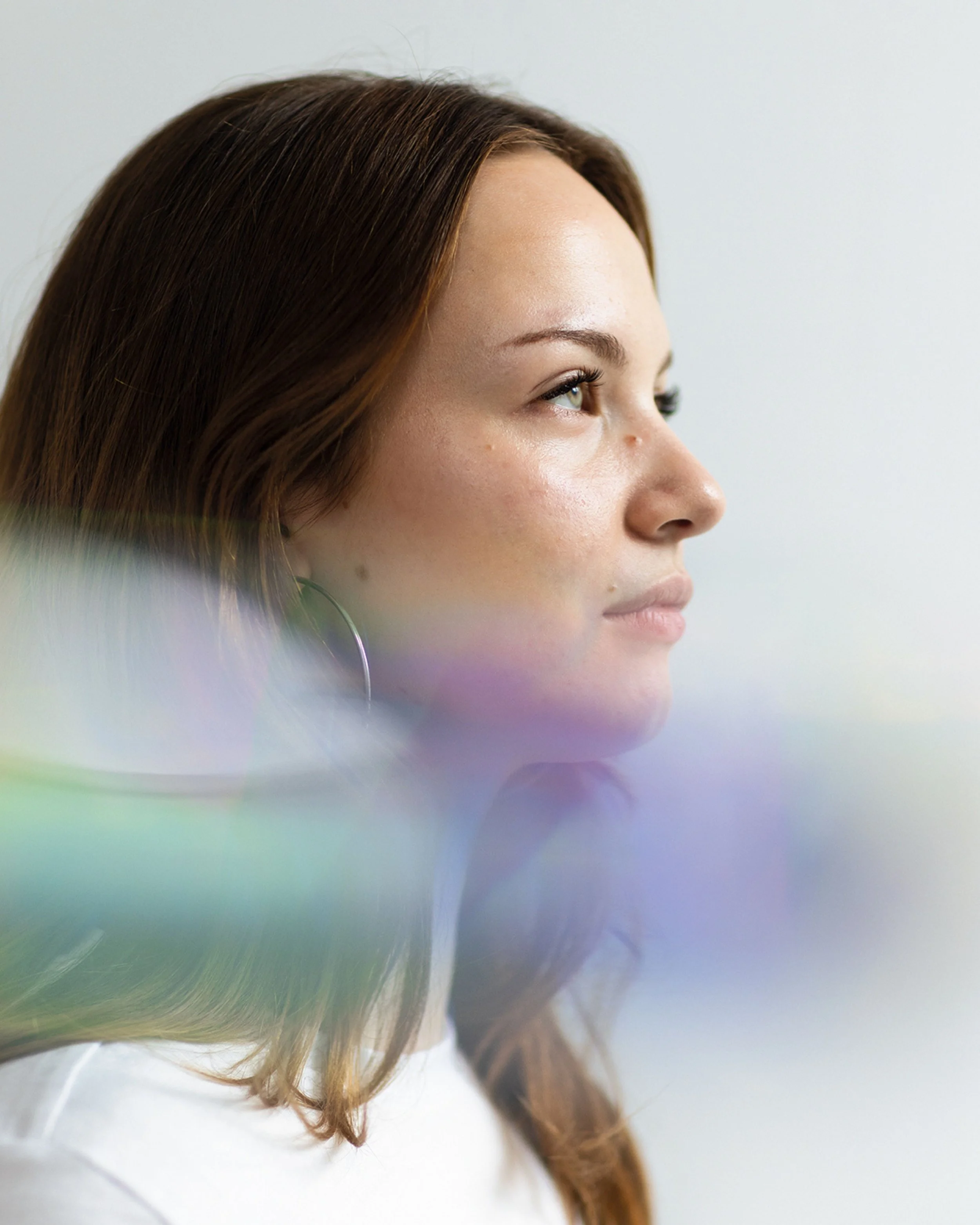 Side view of a woman with brown hair and light skin, looking to the right, against a plain light background.