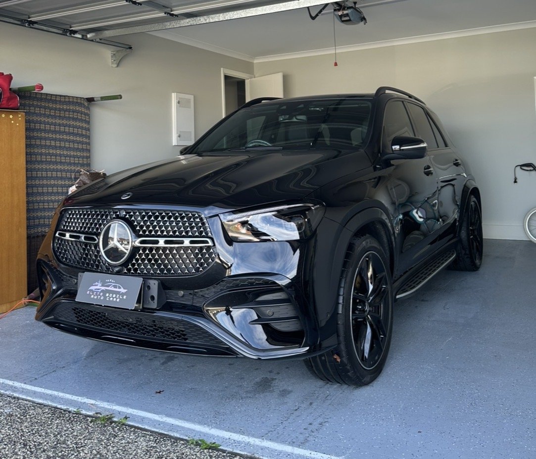Black Mercedes-Benz SUV parked in a garage with a white wall and ceiling.