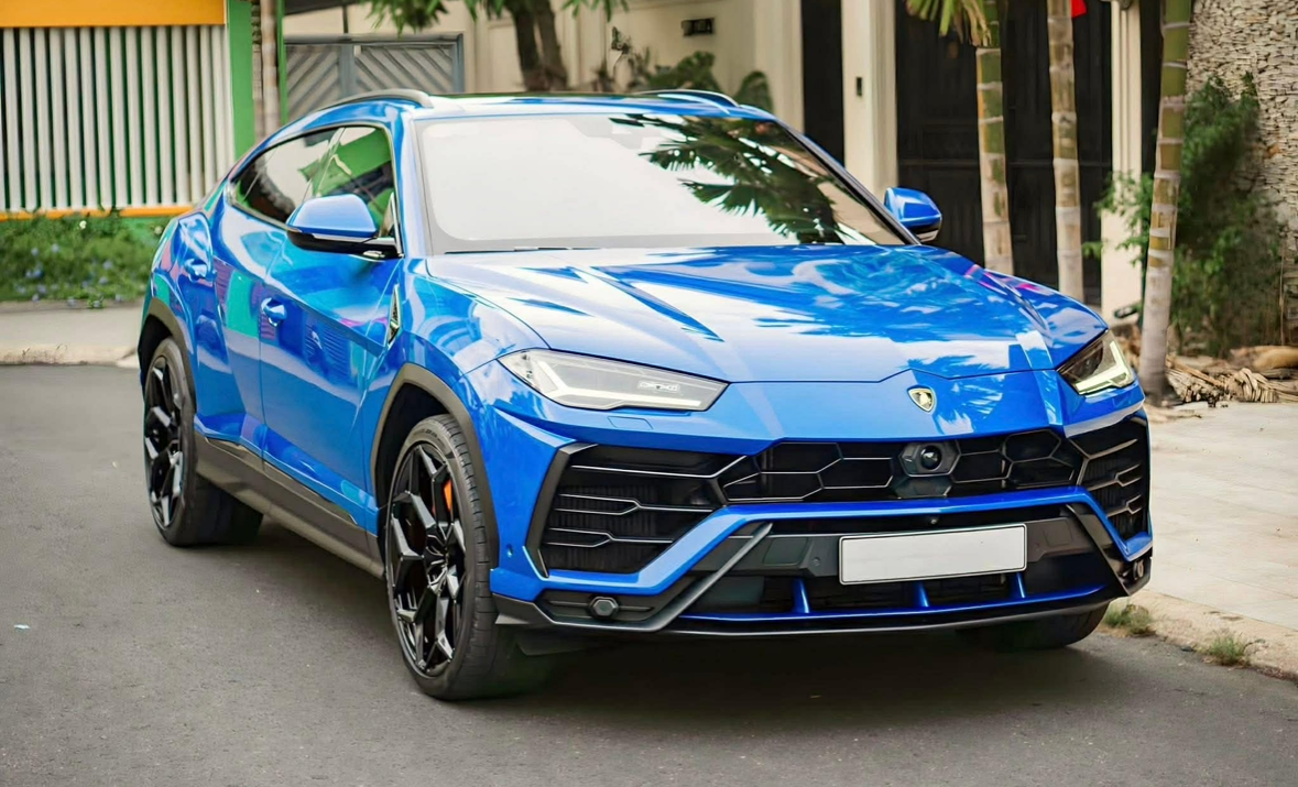 Blue Lamborghini SUV parked on a residential street with trees and a house in the background after getting a full mobile car detailing service