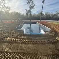 Underground swimming pool under construction, surrounded by dirt and construction equipment
