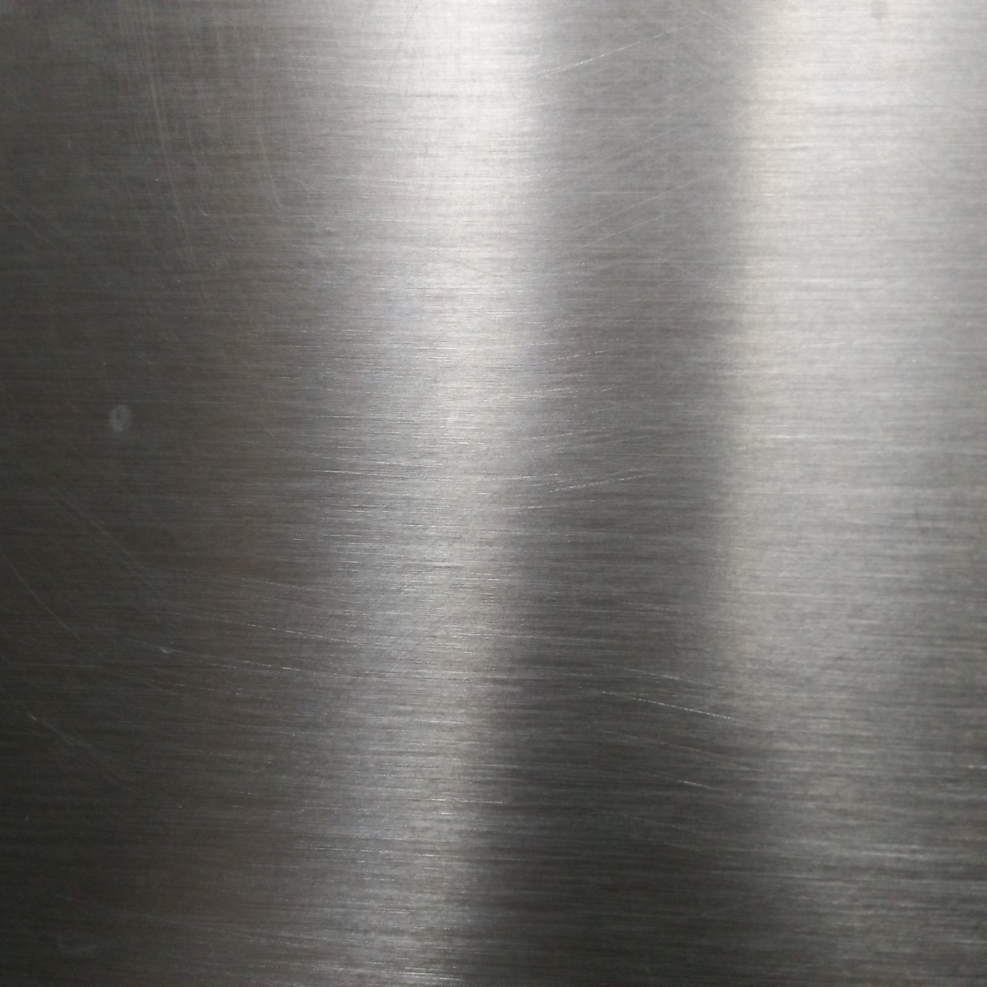 Close-up of a smooth, brushed metal surface with faint scratches and circular patterns.