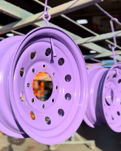 Multiple purple metal wheels hanging from hooks in a store display.