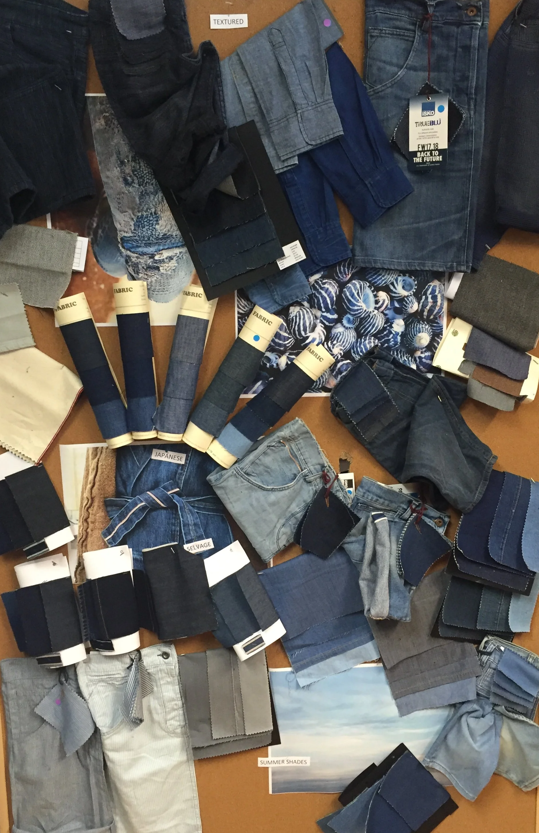 Collection of denim and fabric swatches, jeans, and clothing accessories, organized by shades from dark to light, labeled with tags such as 'TEXTURED,' 'SUMMER SHADES,' and 'JAPANESE.'