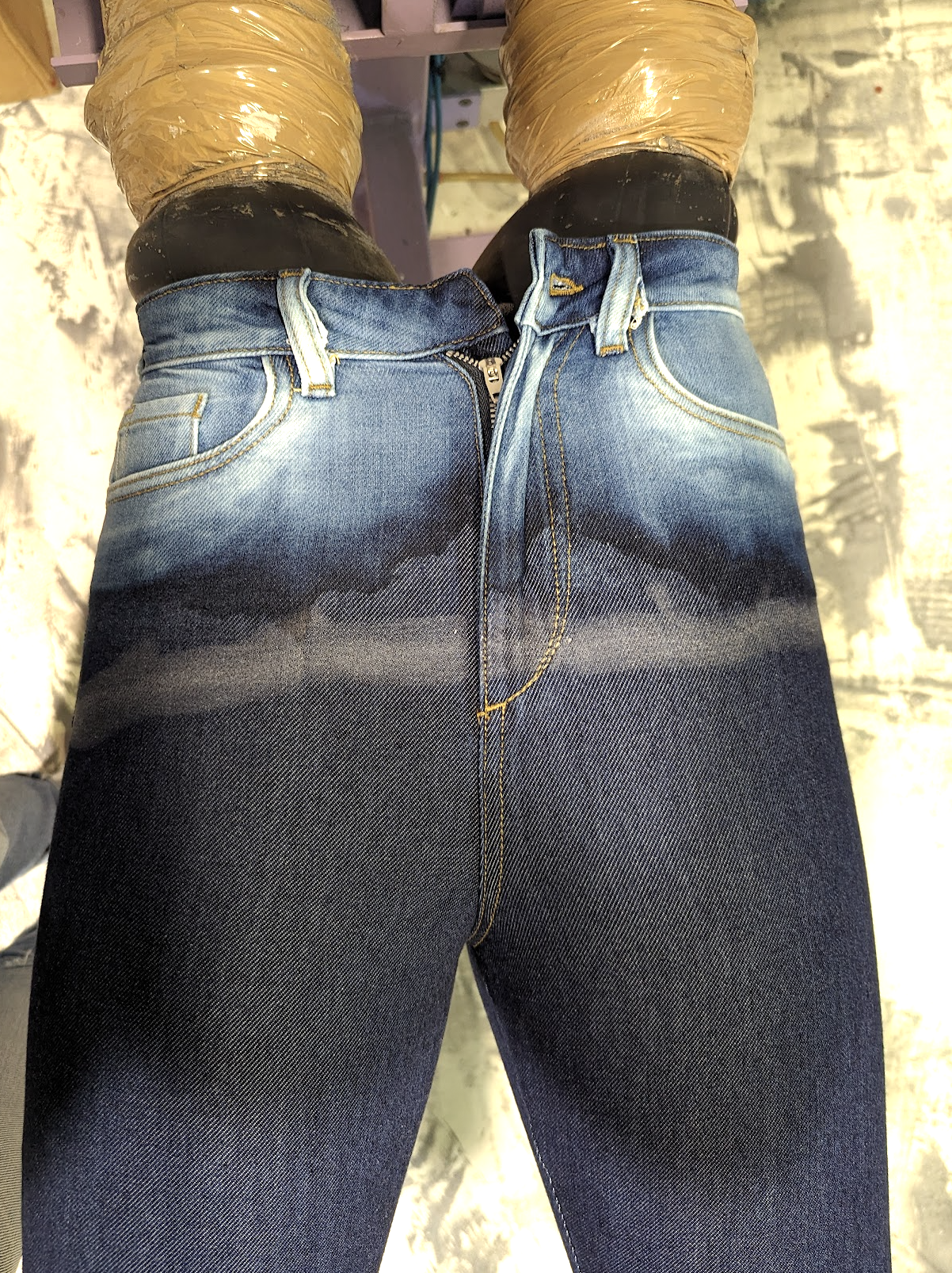 Close-up of wash in progress showing dark blue jeans with a gradient fading downward.