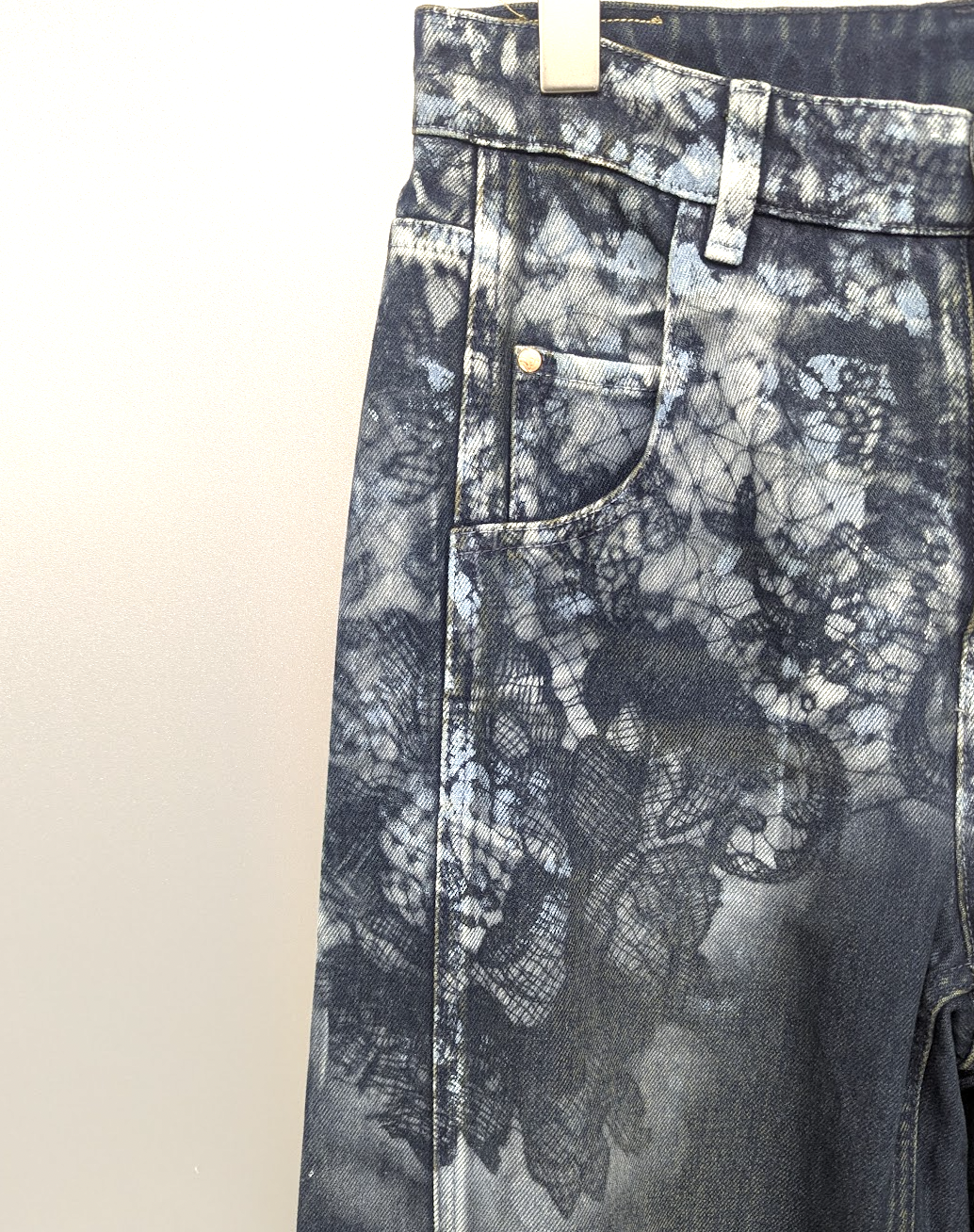 Close-up of a pair of jeans with a black and gray tie-dye or bleach-splattered pattern.