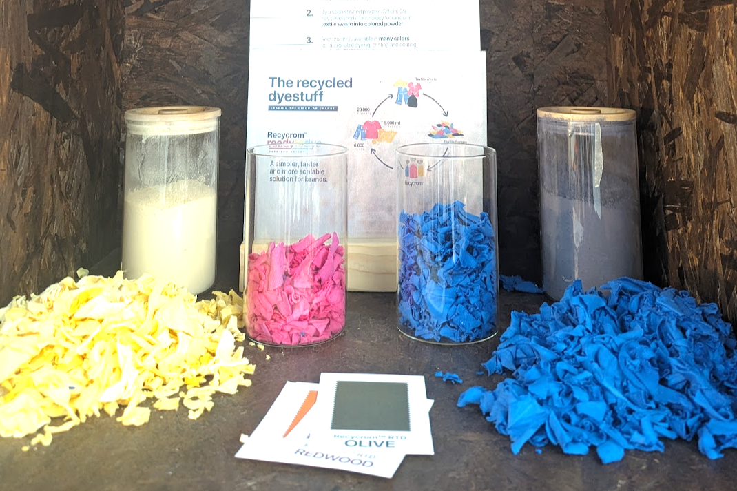 Various containers with fabric dye powders and fabric samples in yellow, pink, and blue.