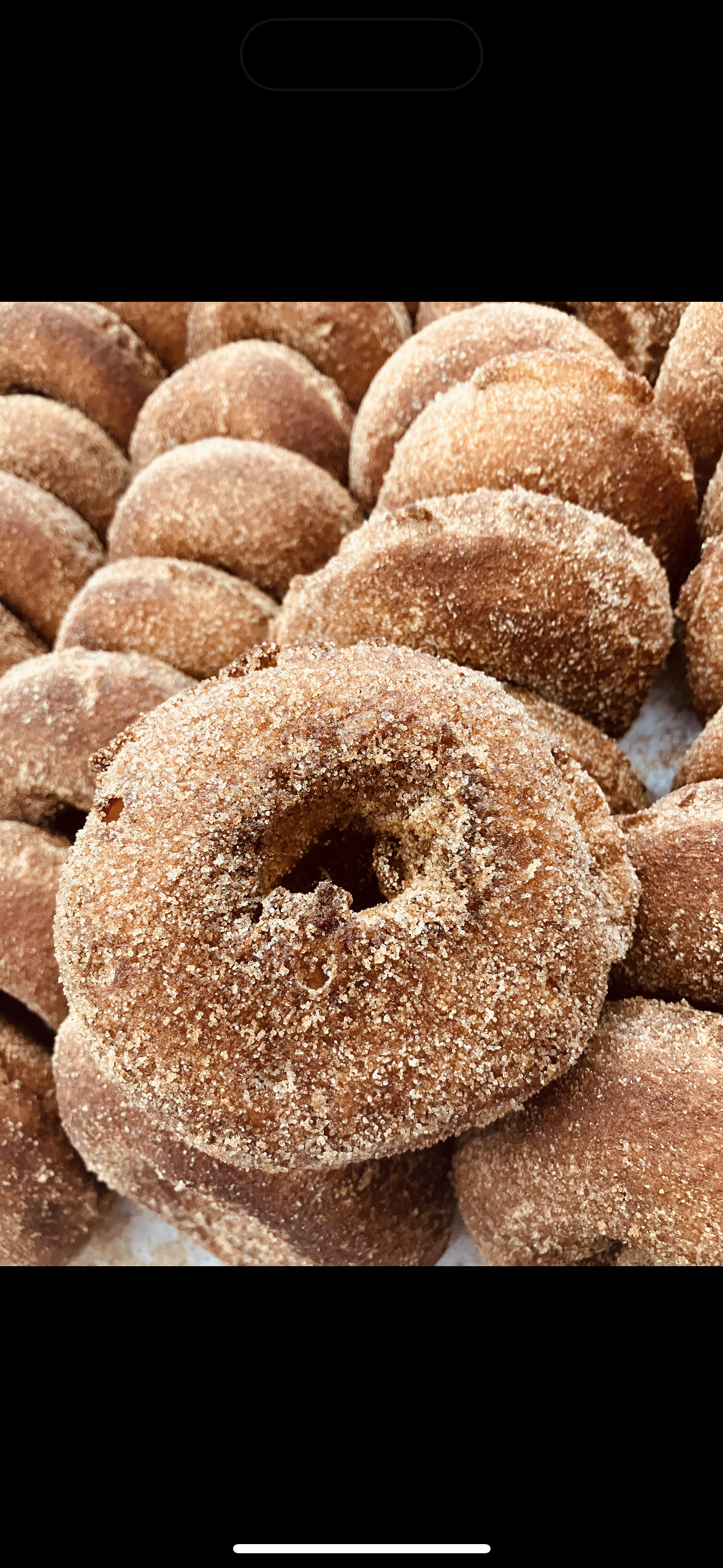 Close-up of a pile of sugar-coated donuts with a hole in the center.