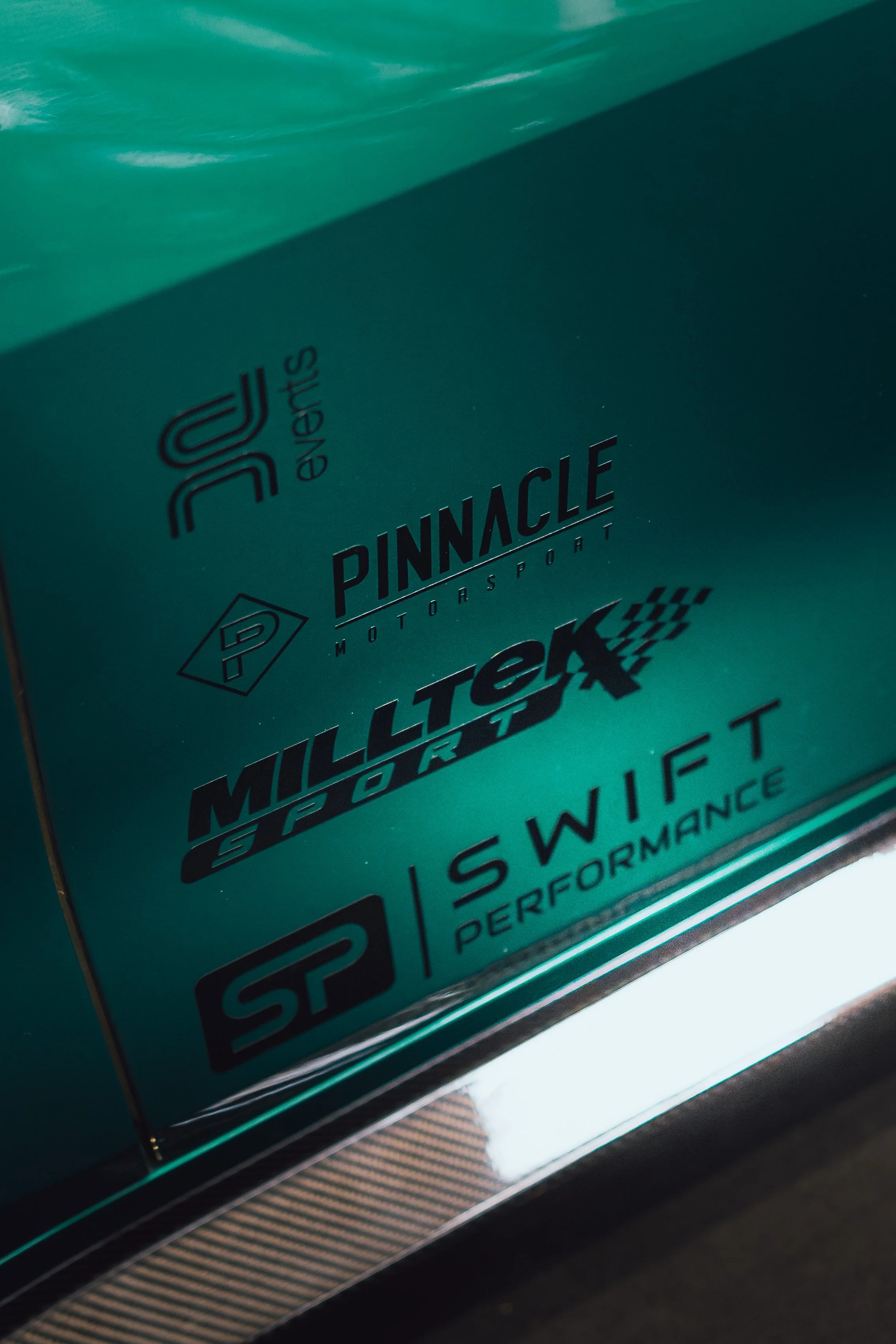 Close-up of a teal-colored box with black and white text and logos, related to automotive performance parts.