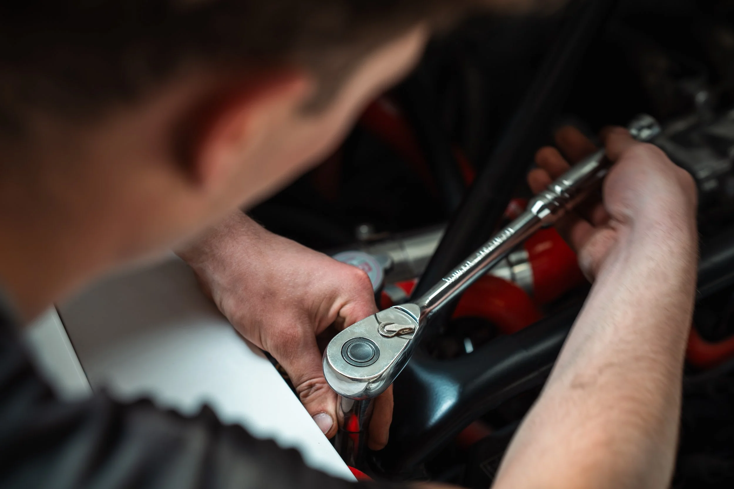 Person using a wrench to work on a motorcycle engine.