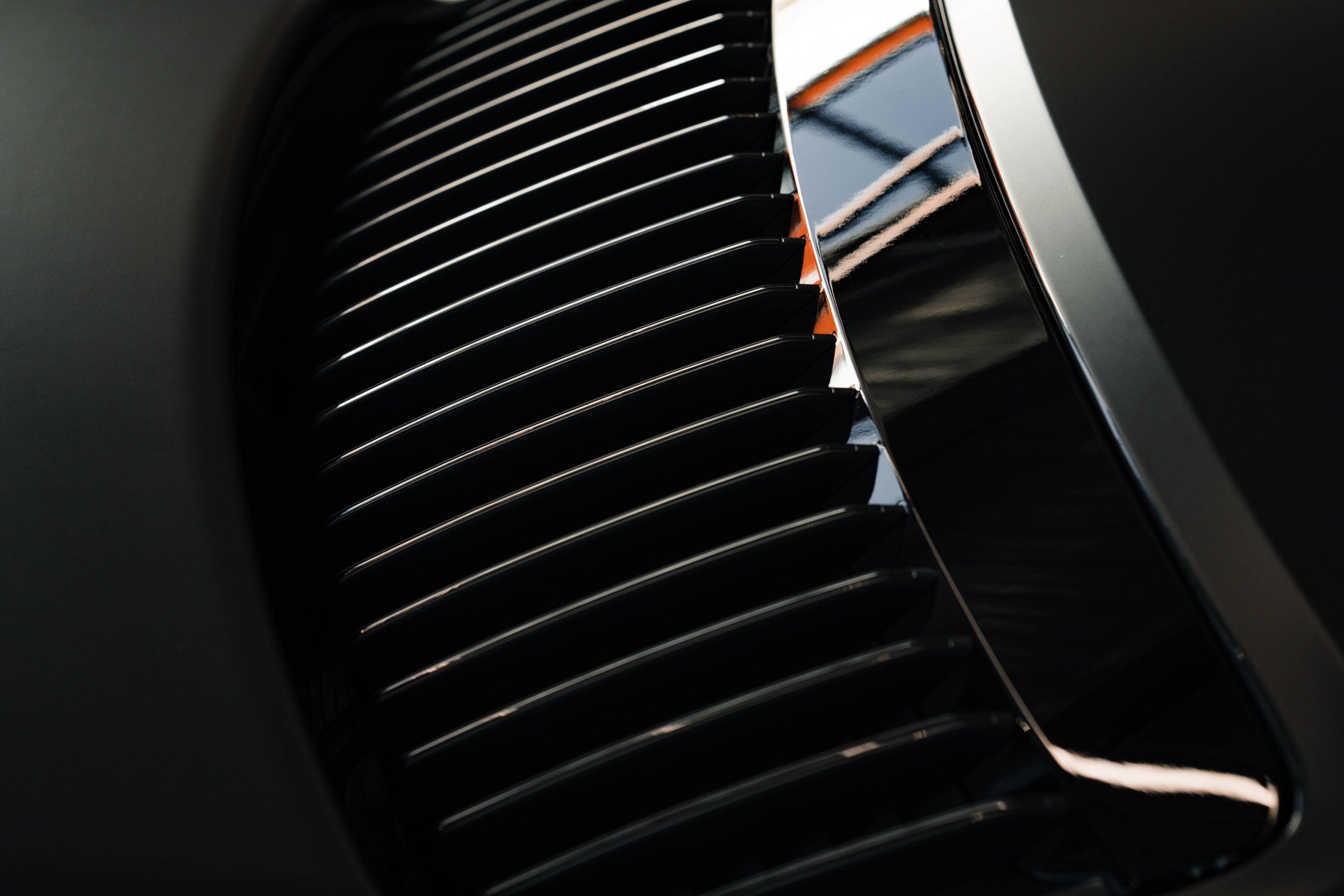Close-up of black car grille with chrome accents.