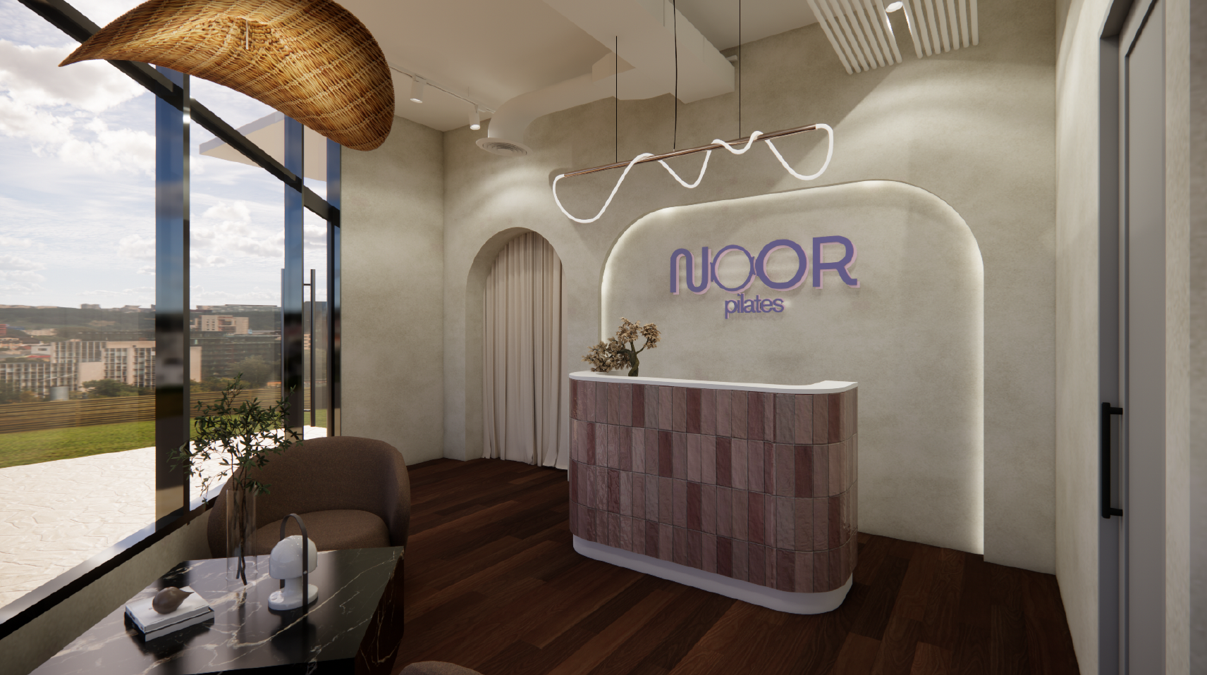 Interior of a Pilates studio reception area with a curved white reception desk, purple neon sign reading 'NOOR pilates,' a flower vase, a brown chair, a small table with decor objects, large floor-to-ceiling windows showing a cityscape, modern lighti