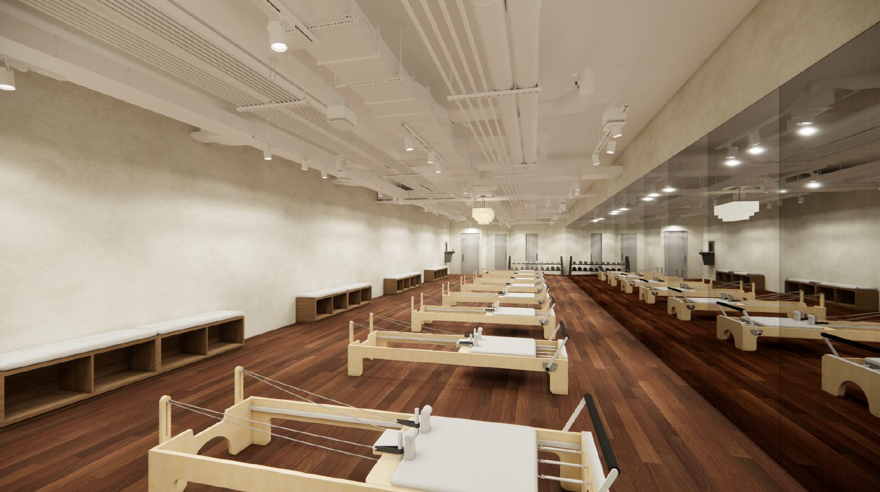 A Pilates or yoga studio with multiple low wooden reformer machines lined up parallel, a mirror wall on the right, and minimalist benches along the left wall with a beige textured wall and ceiling with exposed ducts and track lighting.
