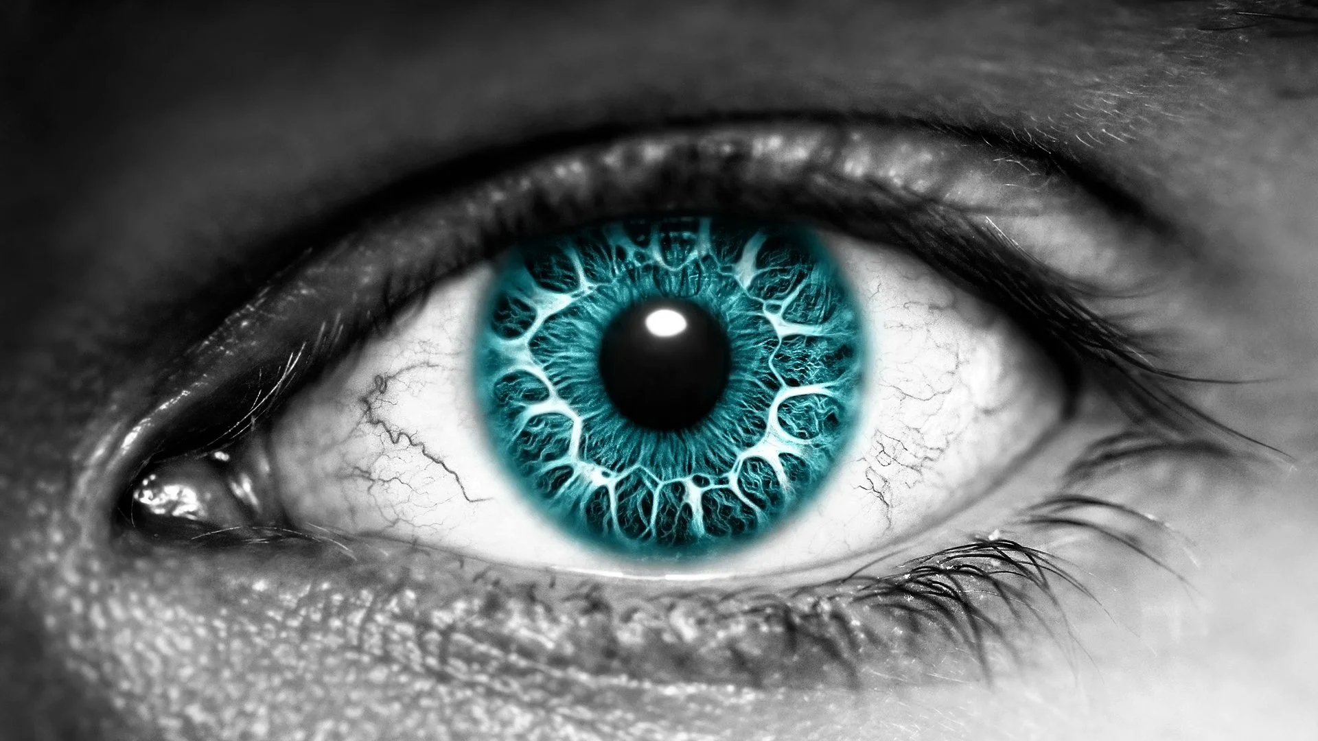 Close-up of a human eye with a bright blue iris, surrounded by black and white tones that emphasize the eye's intricate details.