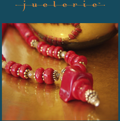 Close-up of a red beaded necklace with silver accents resting on a wooden surface, with a blurred gold-colored bowl in the background, and the word 'Jourelle' in orange text at the top.