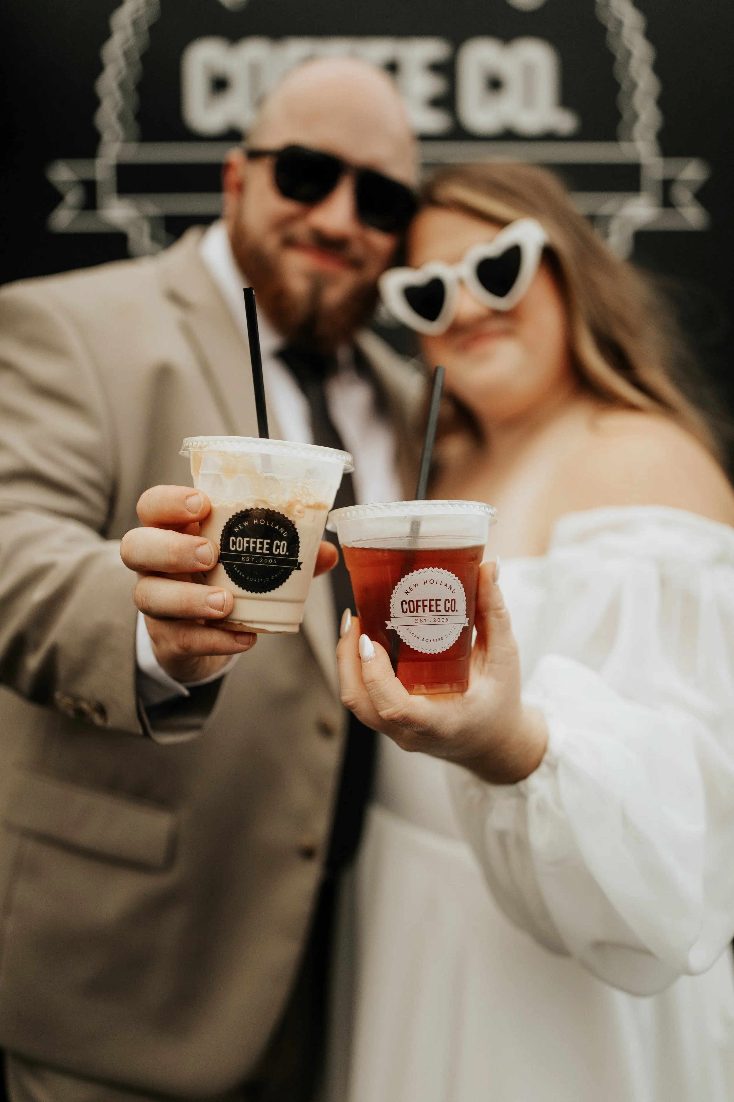 Wedding couple wearing sunglasses toasting with coffee drinks in front of the New Holland Coffee Truck.