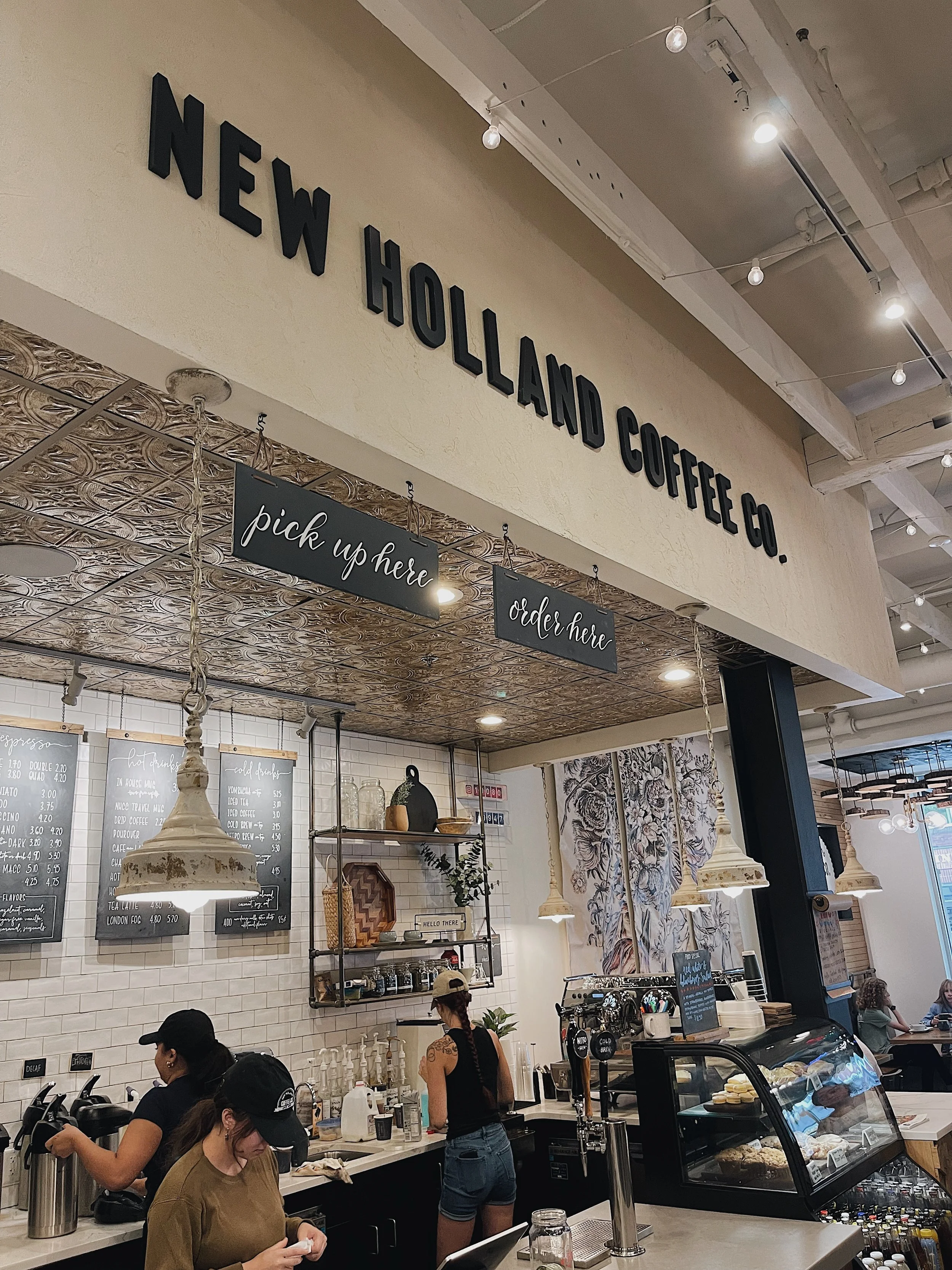 Interior of a New Holland Coffee Lancaster City location with menu, hanging lights, and ordering view.