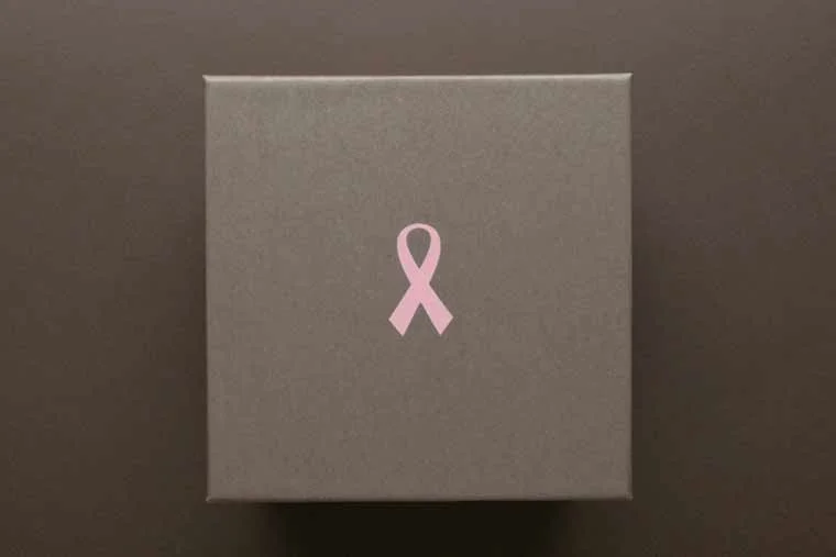 Gray box with pink ribbon symbol on top, likely a gift or donation box.