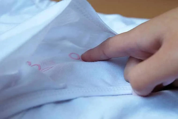 A hand pressing on a small, round, white medical pad or patch attached to a person's skin.