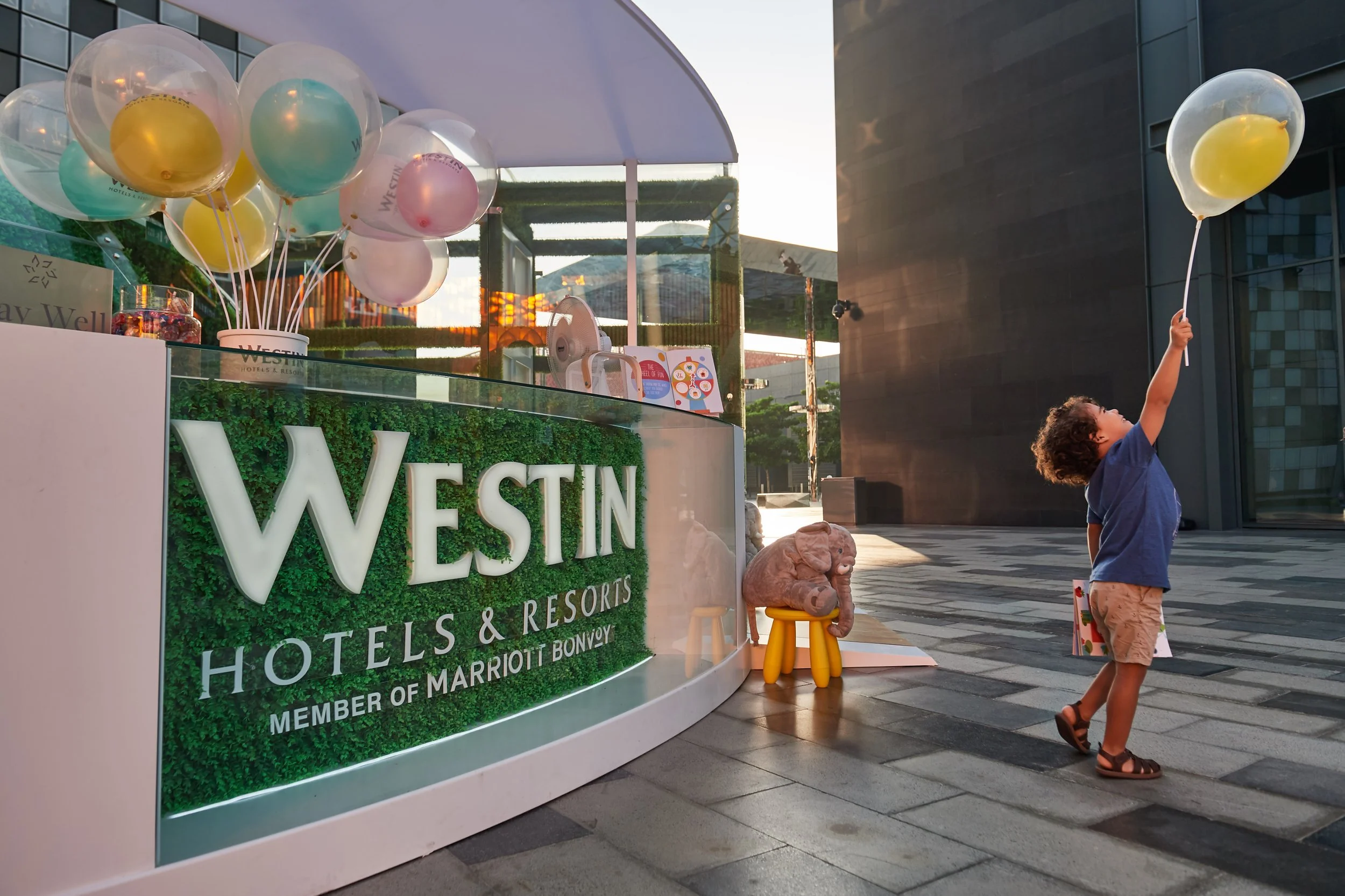 Child reaching for yellow balloon outside the Westin hotel and resort.